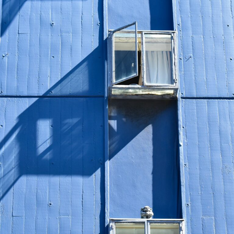 Blue building facade with open window and shadow